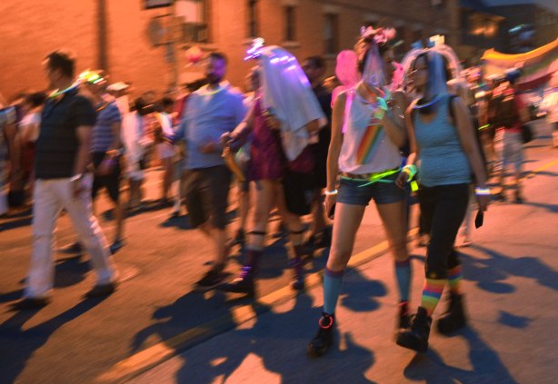 people walking in a parade, glow sticks, some costumes, a woman with pink butterfly wings 