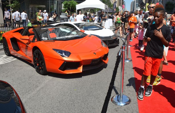 a boy walks past an orange lamborghini