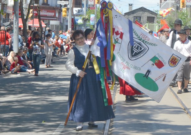 A woman holds a colourful banner in a parade