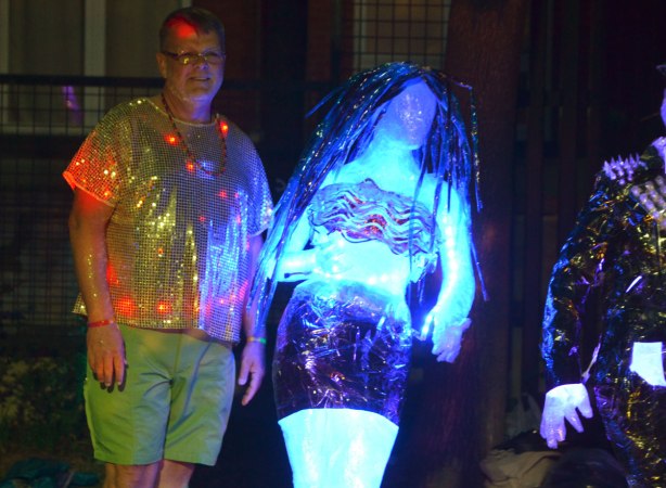 a man with lights in his shirt poses beside two statues that light up 