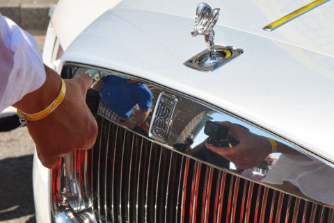 a person using a GoPro to take a picture of reflections in the chrome on the front of a Rolls Royce