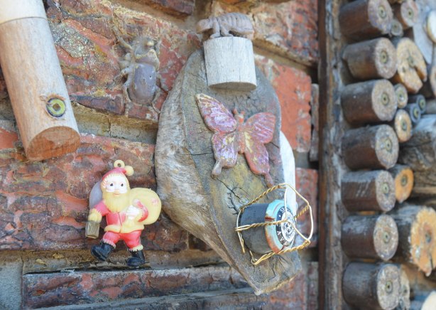 garage in a laneway decorated by Albino Carreira using slices of wood, pool cues, toy figures, and small found objects - a small Santa Claus, beetle, butterly and champagne cork 