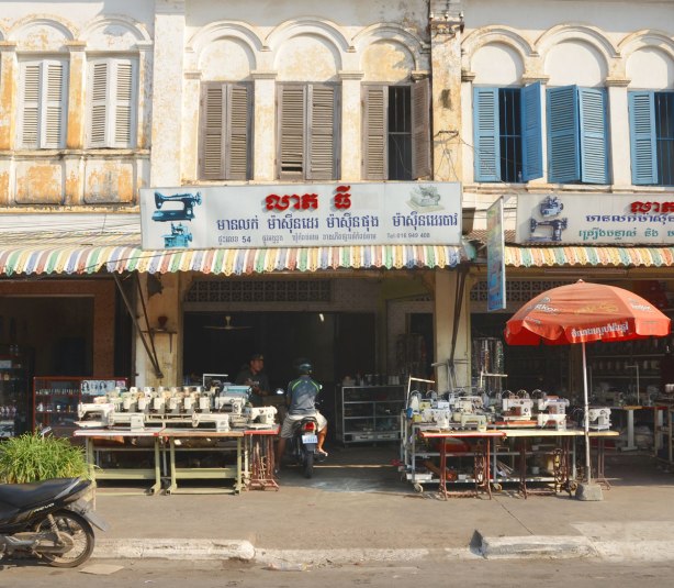 a woman stands beside a table full of old Singer sewing machines that she is selling