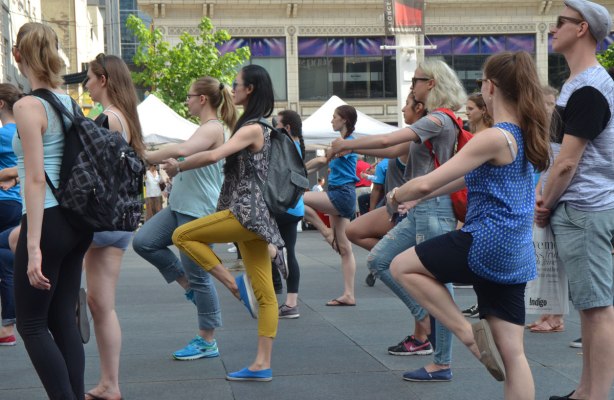 people dancing at Yonge Dundas Square as a group, part of an event called Sharing Dance - one knee up