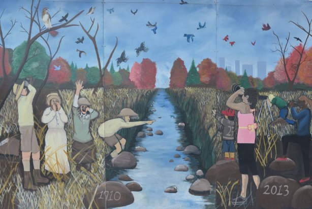 1910 to 2013, mural of past and present along the creek. Kids playing on either side, the past on the left, the present on the right, bird watching, standing in the grass,