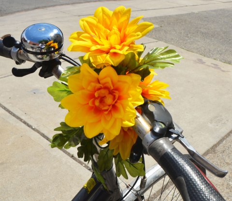 two large yellow flowers attached to the handle bars of a bicycle