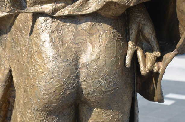 part of a bronze sculptture, a naked bum with a hand beside it.
