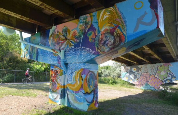 A swirl of colours makes a mural of faces and hands and watery things, on a bent under the Don Valley Parkway