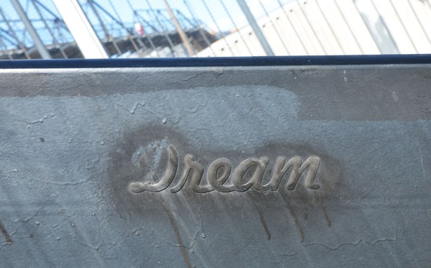 a raised word, 'dream' in cursive that has been stuck on the side of a set of stairs and then painted black to match the steps 