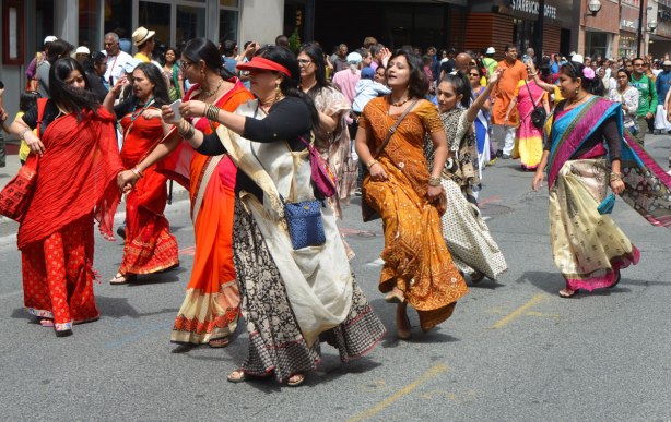 South Asian, Indian, women, in long colourful sarees dancing as they move down Yonge Street in a parade