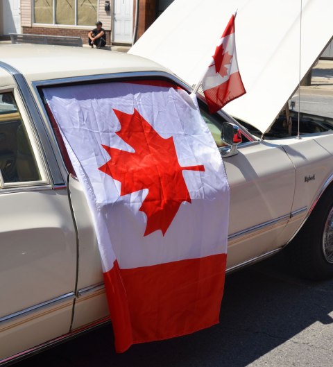 Canadian flag draped over the side of an old car