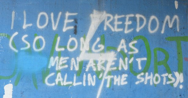 words in white on blue that say I love freedom as long as men aren't callin' the shots. Graffiti 