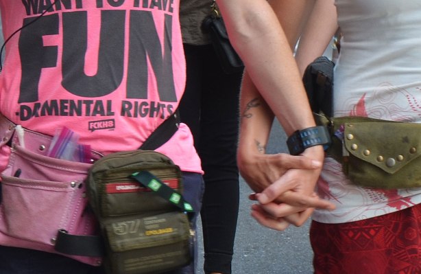 Two people holding hands, one is wearing a pink T shirt that says "Women want to have FUN - damental rights". Closely cropped picture