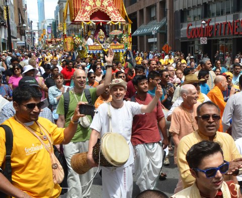 people walking in front of one of the chariots in the Festival of India parade in Toronto