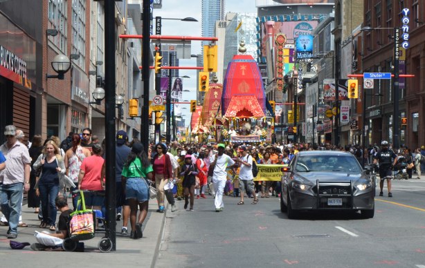 a police car drives slowly in front of a parade as it makes its way down Yonge Street