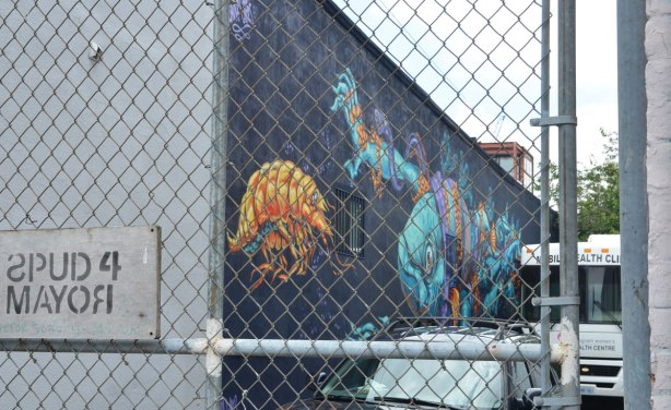 a mural of marine animals on the side of a building, but behind a locked fence