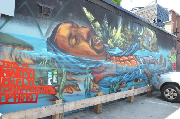 mural of a man lying on his back in the water, words written in red Tona as Marty McFly 