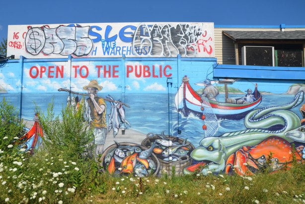 mural with fisherman bringing in a load of fish to the shore, boat in the background, more fish in the foreground. 
