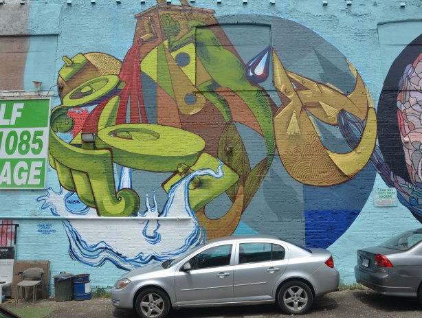 round mural painted by Sermob, car parked in front of it, stylized figures on water