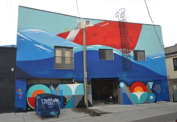 large mural by Peru on the back of a two storey building, a large red ship called the S.S. One Love in the water 