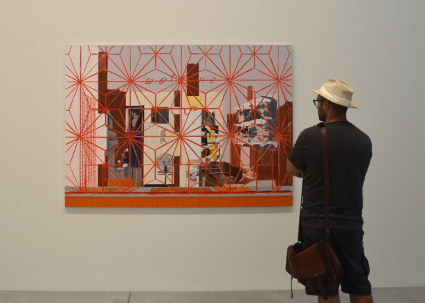 a man in a straw fedora stands in front of a painting called Welcome: Carib by Hurvin anderson, it features a red star patterned grille over the painting, over the window that is in front of the interior scene.