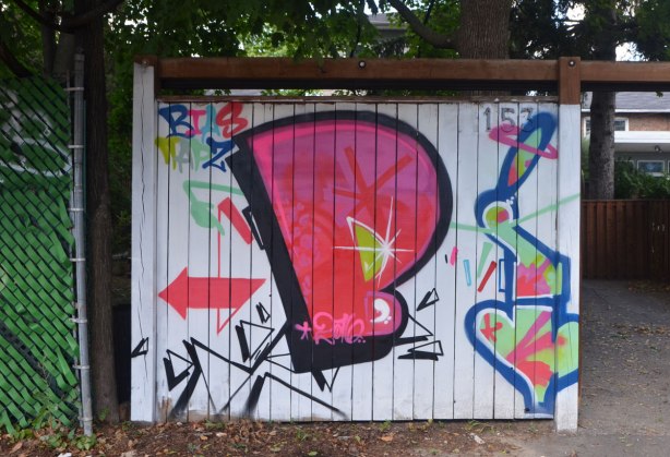 a large fat P in pink on a white wood fence, with some other symbols as well, street art 