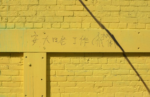graffiti Chinese characters written on a yellow wall. 