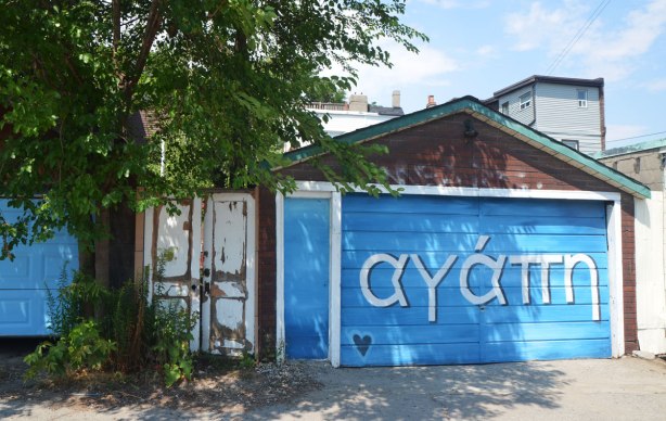 garage door painted bright blue, with the Greek word for love written on it in large letters