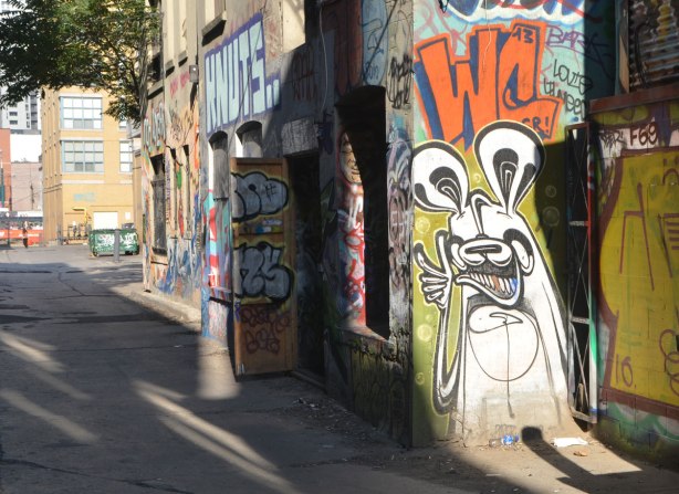 a poser bunny painted on the side of a building, spotlighted by the afternoon sun, the wall behind him is in shadow 