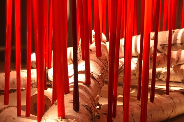 red glass tubes inserted into large birch logs, looks like a campfire with tall flames