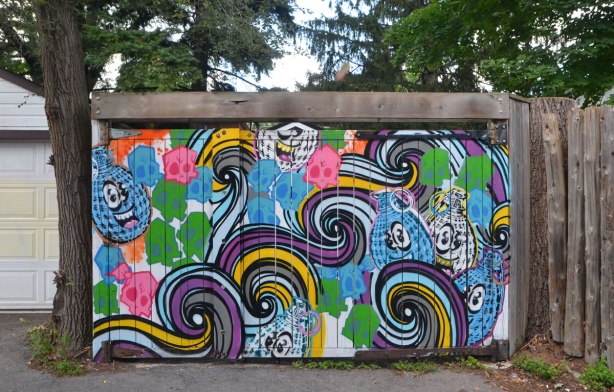 spud bomb and swirls street art on a fence in an alley