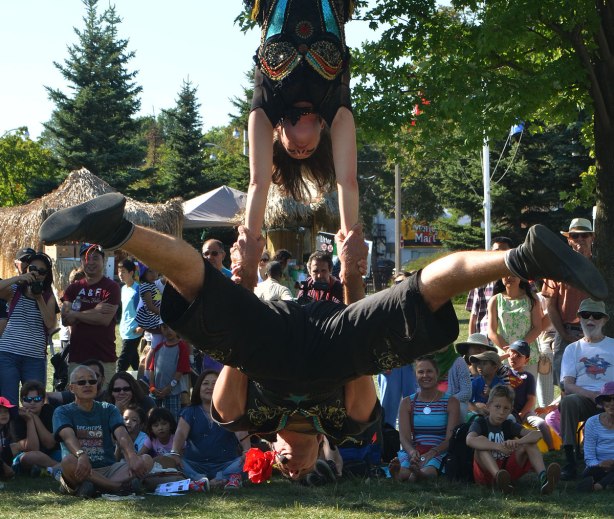 acrobatics - a woman upside known hanging from a trapeze by her knees, holds onto a man 