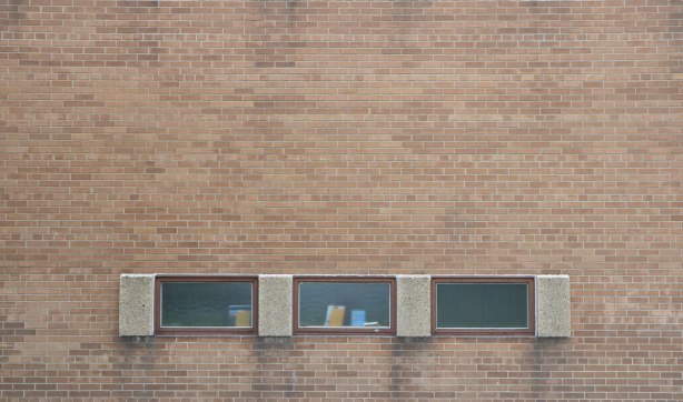 three windows arrange horizontally in a brick wall. windows are not high
