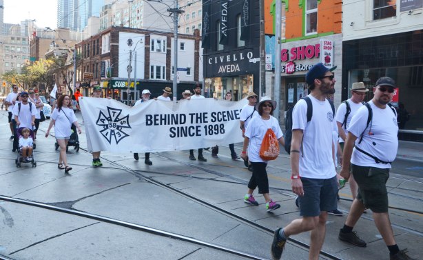 iatse 58, union members walk in a labour day parade with their banner that says Behind the Scenes since 1898 