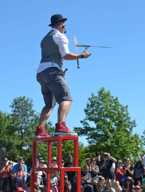 a man stands on top of three stools as he juggles three knives 