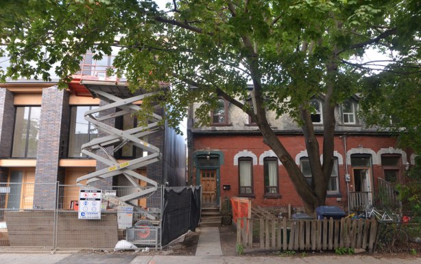 old brick rowhouses to the right, with a large tree in front, and new construction of row houses on the left.