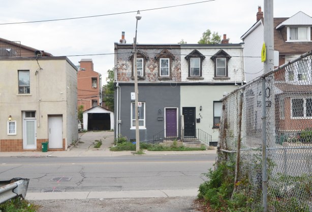 two semi detached houses with mansard roofs, one with a purple front door and one with a black front door. 