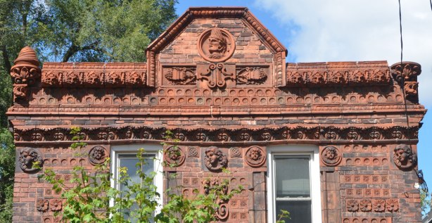 house covered with terra cotta tiles with different designs on them. upper part of front of house