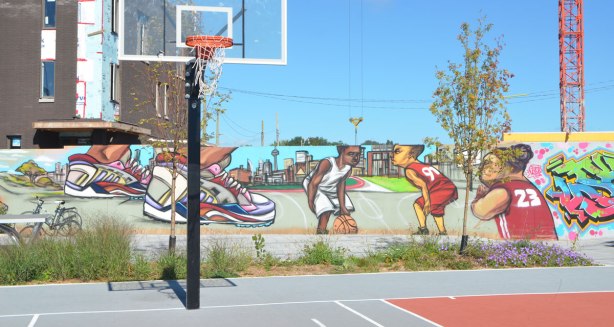 mural of basketball players playing, mural is behind a basketball court, also mural of close up of players feet with running shoes on 