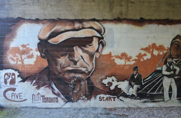 part of a mural under a bridge on the Beltline path, by StART, in brown tones of the hhistory of the railroad in the area (scenes from), an older man in a brown cap