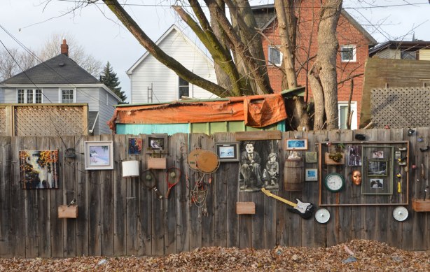 things on a fence as decoration, guitar, pictures, clock, boxes, 