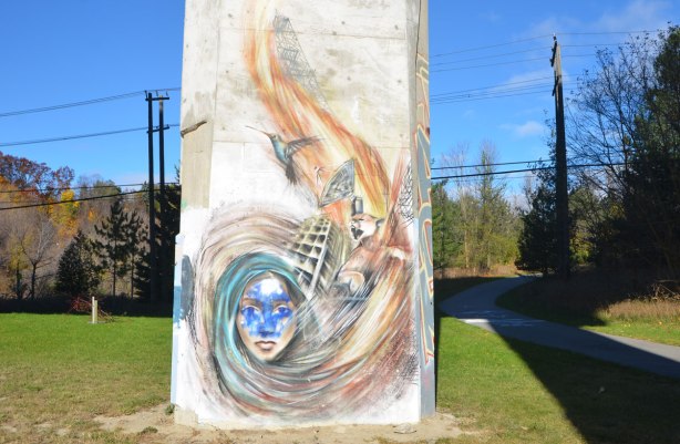street art painting on a pillar under a bridge, wispy picture of a woman with long hair, hair swirls upwards to a satelite dish and a flying bird