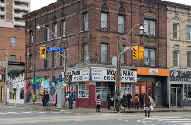 building on the corner of an intersection, Moss Park Discount Store on the corner of Queen East and Sherbourne. People on the sidewalk outside the building. 3 storey brick,