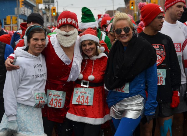 Holly Jolly Fun Run, before the Santa Claus parade, runners getting ready to start the race - group shot, woman in Mrs. Santa outfit, man in ho ho ho toque and red Santa jacket, woman in blue and another woman in a white Toronto hoodie 