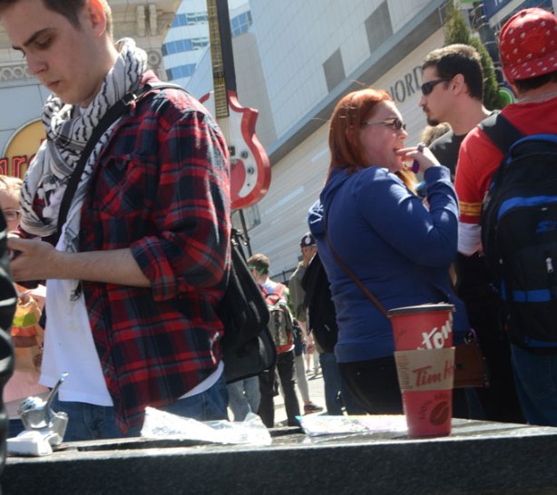 a red ti hortons coffee cup sits on a ledge, people around it, all with their backs to the cup