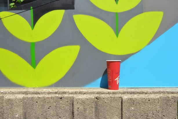 painting of stems with leaves, stylized, with a red Tim Hortons coffee cup at the bottom of one of the stems. 