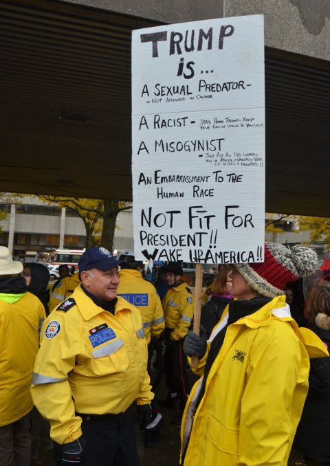 people holding protest signs, talking to the police on duty at the rally to protest against Donald Trump