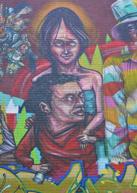 part of a larger mural of elicser and Troy Lovegates, colourful people, A woman stands behind a seated man. 
