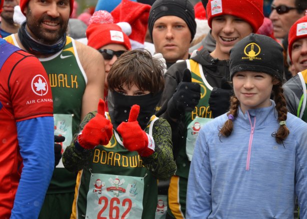 Holly Jolly Fun Run, before the Santa Claus parade, runners getting ready to start the race - a boy with black scarf over most of his face, wearing red gloves, gives a two thumbs up