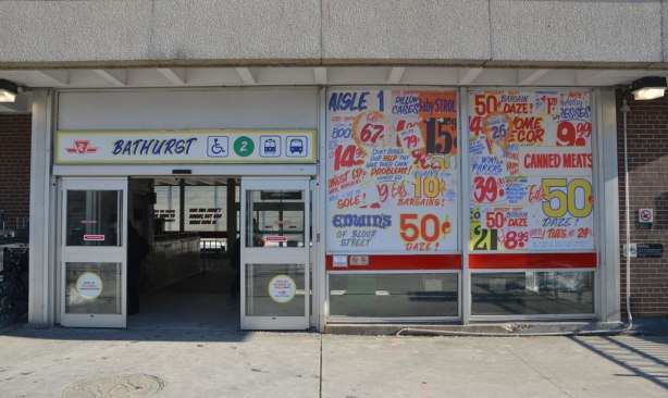 sign maker from Honest Eds store has redone some of the signs in Bathurst subway station plus, he has added some Honest Ed type promo signs around the station - on the window of the station, The window beside the main entrance has been covered with fake ads. 